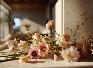Soft blush faux flowers and delicate spring stems scattered across a sunlit table in a luxury interior by True Bloom Floral™