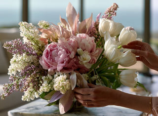 Luxury faux floral arrangement with pink peonies, white tulips, lilacs, and soft spring blooms being styled by hand in a modern coastal home by True Bloom Floral™