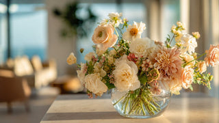 Elegant faux floral centerpiece featuring peach dahlias, cream roses, ranunculus, and blush accent flowers styled in a modern glass vase by True Bloom Floral™
