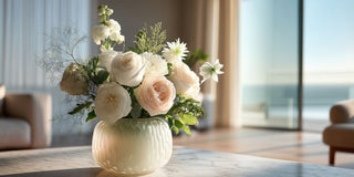 Blush and white floral arrangement in a small textured ceramic vase styled on a marble table in a bright modern living room