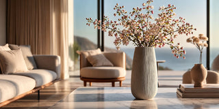 Faux cherry blossom arrangement in a tall ceramic vase styled in a sunlit modern interior with soft neutral tones