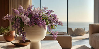 Faux lilac arrangement in a wide mouth vase styled in a sunlit modern interior with soft neutral tones