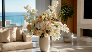 A large floral arrangement with sculptural white bougainvillea stems and florals in a vase in a marble coffee tale of a luxury  modern home with ocean views