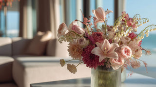 Styled lily of the valley in a glass vase with other summer florals such as stargazer lily, lisianthus and dahlias, in a clear glass vase on a marble table of a coastal home 