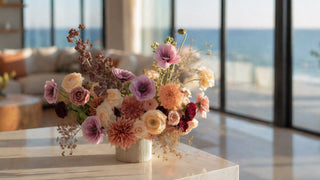 Light purple buttercups, ranunculus, roses and purple blossom branches styled in a modern vase on a marble table in a modern coastal home