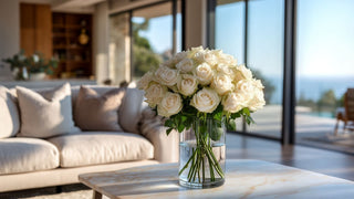 A luxury faux white rose bouquet in a glass vase, styled on a marble table in a bright coastal living room