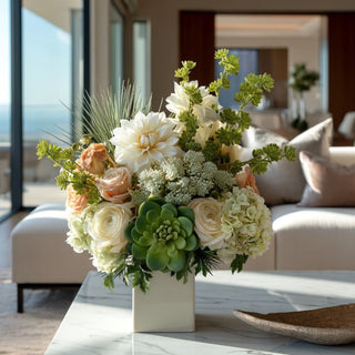 42-inch green faux succulent spray styled with warm peach and ivory florals in a rounded vase for a full layered summer faux floral arrangement on a marble surface