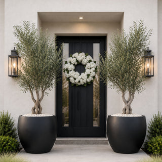 True Bloom white hydrangea wreaths styled on dark black wooden front door with green planters, creating a fresh year-round entryway look that works beautifully for spring, summer, fall, winter, and holiday styling.