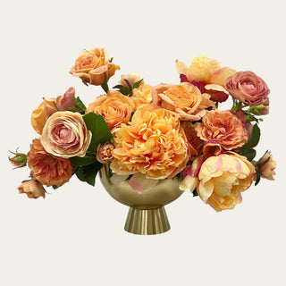 Apricot Garden premade floral arrangement shown in a gold metal vase with apricot, peach, cream, and blush mixed real touch and faux florals for coffee table, dining table, entry console, kitchen island, and bedroom dresser styling.