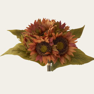 Close-up of traditional faux sunflower blooms with layered fabric and polyester petals in brown, orange and burgundy, dark textured centers and olive leaves.
