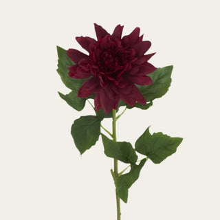 Close-up of burgundy real touch dahlia bloom showing layered petals, deep saturated color, and a soft floral surface with traditional faux green leaf detail.
