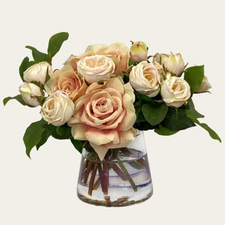 Champagne Rose Manor True Bloom Real Touch premade floral arrangement shown in a clear glass vase with champagne roses, cream rose buds, pale blush accents, and green foliage for coffee table, bedside table, bathroom vanity, kitchen island, and entry console styling.