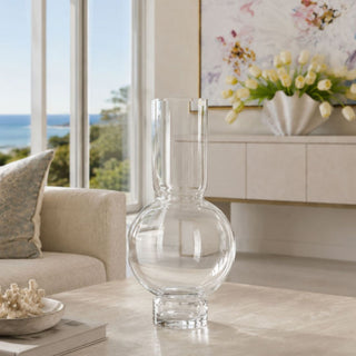Clear Monceau Glass Vase styled on a stone coffee table in a coastal-inspired living room, designed for tall faux florals, tulips, hydrangeas, branches, and seasonal arrangements.