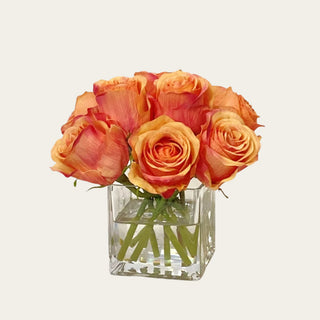 Coral Rose faux floral premade arrangement shown in a clear glass square vase with compact coral, peach, and orange rose blooms for coffee table, bedside table, bathroom vanity, kitchen shelf, and small console styling.