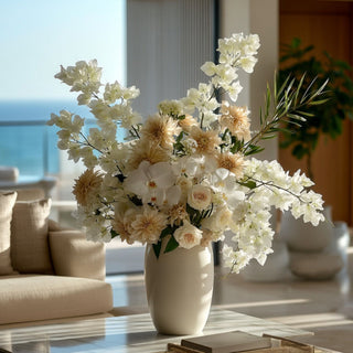 Luxury floral arrangement featuring creamy  white bougainvillea stems and other florals to create a summer inspired arrangement. in a vase on a marble coffee table in a luxury coastal home with ocean views