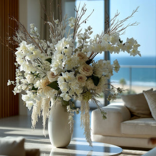 Luxury winter inspired floral arrangement featuring creamy white bougainvillea stems in a white vase on a marble coffee table in a luxury coastal california home with ocean views, 