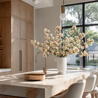Creamy white True Bloom real touch blossom branches arranged in a Large white ceramic loop vase on a marble kitchen island with warm wood cabinetry and natural window light