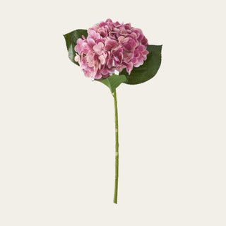 Dark pink True Bloom real touch hydrangea stem with a full rounded bloom, faux green leaves, and a faux stem, ideal for year-round floral arrangements because its richer pink tone pairs beautifully with spring florals, summer whites, fall mauves, and winter or holiday neutrals.