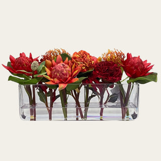 Ember Reserve faux floral premade arrangement shown in a clear rectangular glass vase with red, ember orange, coral, rust, and green faux florals for low-profile dining table, coffee table, kitchen island, and console styling.