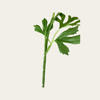 Detail view of the flexible plastic wired stem and faux green leaves on a yellow real touch triple bloom ranunculus stem for shaping in floral arrangements.