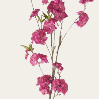 Close-up of fuchsia cherry blossom branch with layered faux blooms and small green leaves, used by designers to add bright seasonal color and airy movement to spring and summer floral arrangements.