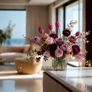 Fuchsia True Bloom real touch tulips arranged in a clear square glass vase with soft green leaves and naturally curved stems for a bright faux floral centerpiece.

