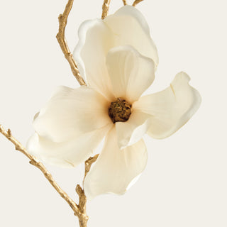 Close-up of creamy white faux magnolia petals with softly shaped texture, a detailed floral center and sculptural metallic gold branching.