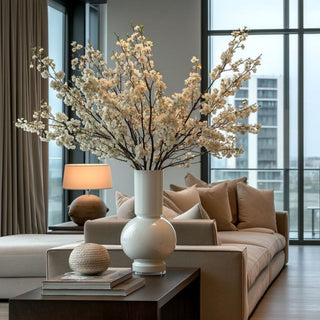 Glossy White Monceau Glass Vase styled with white blossoming branches in a warm modern living room, ideal for tall faux florals, seasonal branches, greenery, and year-round floral arrangements.