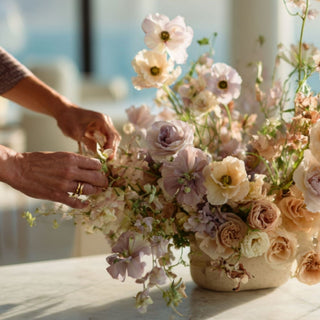 Woman's hands arranging flowers in a vase with a blurred background