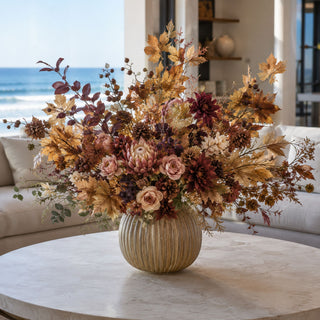 Maple Leaf Spray with Berries and Pinecone styled in a fall floral arrangement with golden maple leaves, brown berries, pinecones, blush roses, protea-style blooms, burgundy dahlias, and layered autumn greenery in a ribbed vase on a marble coffee table.