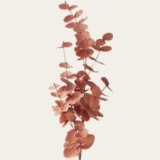 Close-up of polyester and plastic eucalyptus leaves in terracotta, dusty coral and copper-orange tones with layered texture and natural color variation.