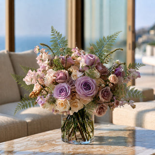 36 inch real touch royal fern stems styled in a pastel faux floral arrangement with lavender roses, cream roses, blush flowers, and a clear glass vase in a bright coastal living room, showing how the fern adds airy greenery, height, and natural movement.
