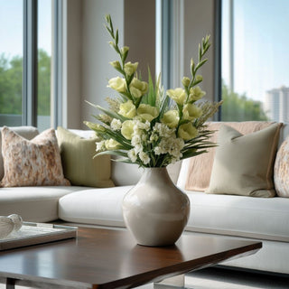 Soft chartreuse True Bloom gladiolus stems styled in a neutral ceramic vase with white florals and soft greenery on a wood coffee table in a light-filled living room