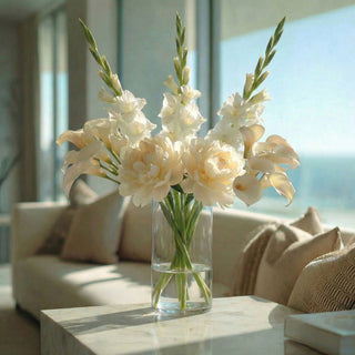 Step 3 three of building an arrangement using movement stems of creamy white tulips added to the peony and gladiolus. style din a clear vase on a marble table of a modern coastal home style 