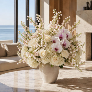 Real Touch Lily of the Valley Bundle styled in an arrangement with other pink and mauve florals in a vase on a marble coffee table in a luxury coastal home with ocean views