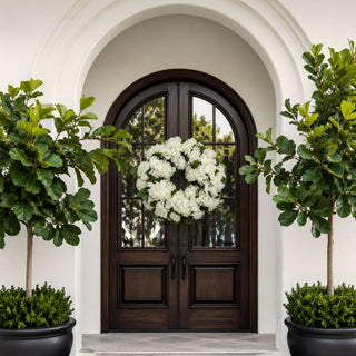 True Bloom white hydrangea wreaths styled on double wooden front doors with matching white hydrangea planters, creating a fresh year-round entryway look that works beautifully for spring, summer, fall, winter, and holiday styling.