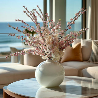 56 Inch Pink Confetti Branch Stem styled in an arrangement in a glossy white glass vase on a maple coffee table in a luxury california coastal home. 