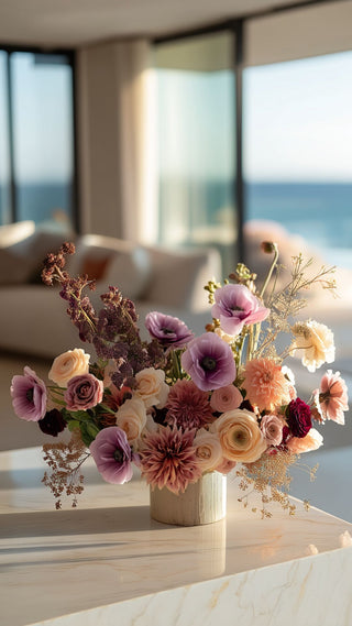 Mixed Faux Floral Arrangement featuring lavender buttercups, ranunculus, blossom stems and dahlias in a contemporary vase on a marble table in a modern coastal home 