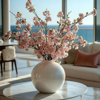 Light purple True Bloom Real Touch blossom branch styled in an arrangement in a round glossy white glass vase on a marble coffee table in a luxury coastal home