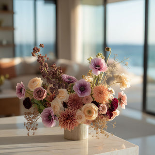 Light purple real touch buttercup styled in a luxury floral arrangement with blush, cream, mauve, and burgundy faux flowers on a marble kitchen island in a bright modern coastal home.