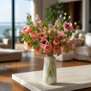 Coral real touch buttercup stems styled in a tall vase with blush florals and green buds on a dark wood coffee table in a modern living room