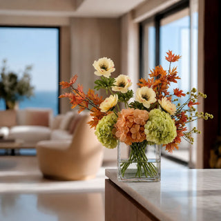 Light yellow real touch buttercup stems styled in a square glass vase with green hydrangeas, peach florals, and autumn branches on a coffee table in a modern living room