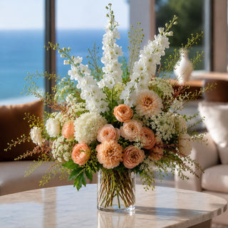 White true bloom real touch delphinium styled in a beautiful floral arrangement in a  clear glass vase on a marble coffee table in a luxury living room of a coastal home 