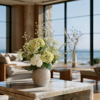 White and green real touch hydrangea arrangement with airy flowering branches displayed in a weathered stone vase on a marble coffee table in a luxury coastal living room. Elegant faux florals designed for timeless home décor and year-round beauty.