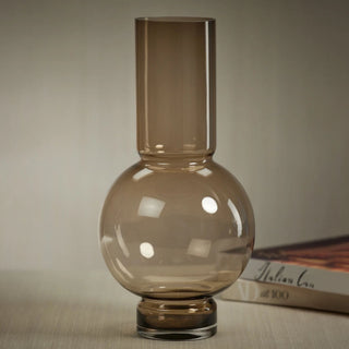Taupe Monceau Glass Vase styled with a sculptural rounded glass base and tall cylindrical neck, designed for warm neutral faux floral arrangements with roses, tulips, hydrangeas, peonies, branches, and greenery.
