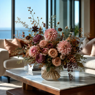 Luxury faux dried pink dahlia floral arrangement with blush roses, ranunculus and olive foliage in a glass vase for elegant late summer and fall home décor