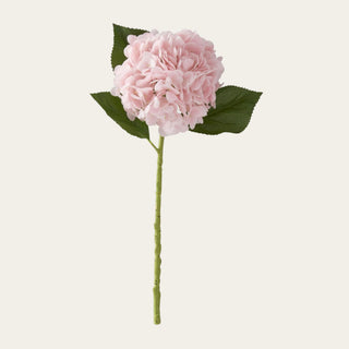 Light pink True Bloom real touch hydrangea stem with a soft rounded bloom, pale pink petals, faux green leaves, and a faux stem, ideal for year-round floral arrangements because its gentle pink color pairs beautifully with spring pastels, summer whites, fall mauves, winter neutrals, and holiday champagne tones.