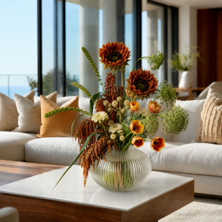 True Bloom Floral orange Real Touch sunflower stems styled in an elegant autumn floral arrangement with orange tulips, ivory blooms and greenery in a ribbed glass vase in a luxury modern living room