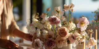 Woman with a beautiful floral arrangement styled in a vase on a table  with a blurred background