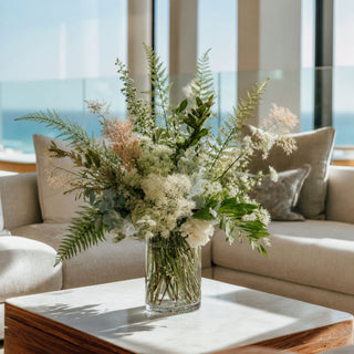 Real touch white and green faux floral arrangement with ostrich fern stems, eucalyptus, and soft botanical textures in a modern glass vase, styled in a luxury neutral living room. Premium artificial flowers by True Bloom Floral.
